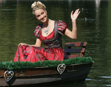Model Regina Deutinger in the world's most expensive Dirndl dress waves to photographers as she sits in a boat during the Dirndl presentation in Munich, September 13, 2006. 