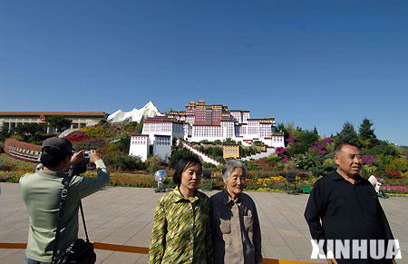 Tourists pose for photos in front of a model of the Potala Palace on the Tiananmen Square.