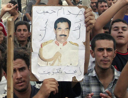 Supporters display a picture of former Iraqi leader Saddam Hussein during a demonstration in Tikrit, 175 km (110 miles) north of Baghdad, November 5, 2006. A visibly shaken Saddam Hussein was found guilty of crimes against humanity on Sunday and sentenced to hang by the U.S.-sponsored court that has been trying him in Baghdad for the past year.