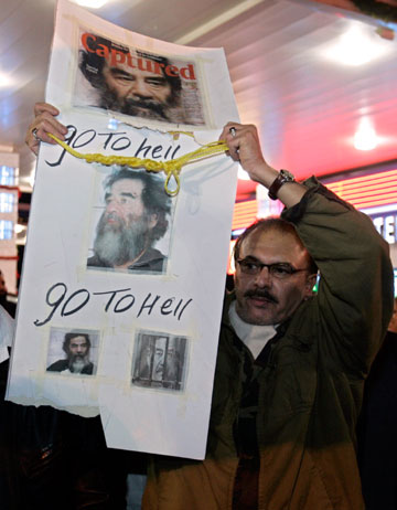 An Iraqi American holds up a sign with pictures of former Iraqi President Saddam Hussein and a yellow hangman noose in Dearborn, Michigan December 29, 2006, to celebrate the execution of Hussein in Iraq. Saddam Hussein has been executed by hanging, a senior U.S. official confirmed on Friday.