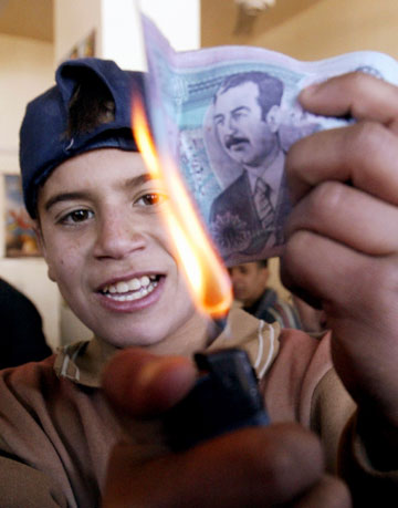 A boy burns a bank note from the time of former Iraqi President Saddam Hussein in Baghdad's Sadr city December 30, 2006 after Saddam's execution. Saddam was hanged at dawn on Saturday for crimes against humanity, a dramatic, violent end for a leader who brutally ruled Iraq for three decades before he was toppled by a U.S.-led invasion in 2003.