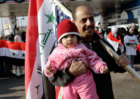 Riyabh Musa, an Iraqi American Shi'ite Muslim, holds his daughter Zaniab and the flags of Iraq and the U.S. as he celebrates the execution of former Iraqi President Saddam Hussein in Iraq, on a street in Dearborn, Michigan December 30, 2006.