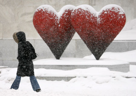 A pedestrian passes a heart sculpture during a snow storm in Montreal February 14, 2007.