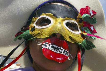 A Salvadoran woman wears a mask and fake lips with the words 