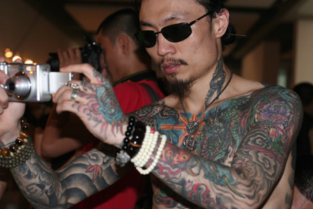 A man with tattoos takes a picture during the Tattoo Show Convention China 2007 in Beijing June 16, 2007. 