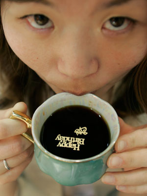 An employee of Tsukioka Co. Ltd poses with a cup of coffee which contains floating gold characters during the 20th Interphex Japan, Asia's largest pharmaceutical industry exhibition, in Tokyo June 20, 2007. According to the company, the edible pure gold helps to refresh human body. The character reads 
