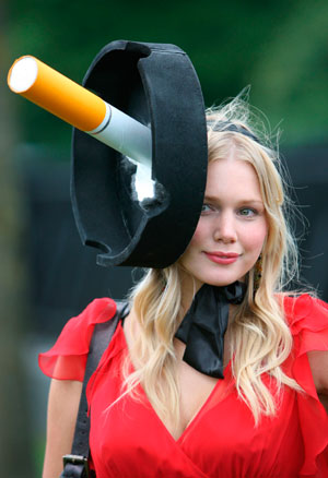 A race-goer with a hat showing a cigarette in an ashtray arrives for Ladies Day on the third day of racing at the Royal Ascot meeting June 21, 2007. 