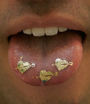 An employee of Tsukioka Co. Ltd displays heart-shaped edible gold pieces on his tongue at the 20th Interphex Japan, Asia's largest pharmaceutical industry exhibition, Tokyo June 20, 2007. According to the company, the edible gold helps to refresh the human body. 