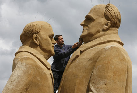 Sand sculptors Andrei Kudrin of Ukraine makes final touches on his sculpture showing former German Chancellor Helmut Kohl (R) and former Soviet President Mikhail Gorbachev during the Sand Sculpture Festival 
