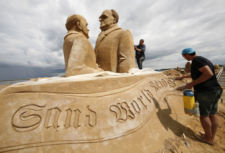 Sand sculptors Andrei Kudrin of Ukraine and Vann Bautista (R) of Spain work on a sculpture showing former German Chancellor Helmut Kohl (R) and former Soviet President Mikhail Gorbachev during the Sand Sculpture Festival 