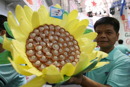 A worker shows a design made of condoms at the 4th China Reproductive Health New Technologies & Products Expo in Beijing July 11, 2007. Condoms of all shapes and sizes were on show at a Beijing fashion show on Wednesday featuring dresses, hats and even lollipops made of the said item.