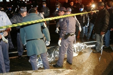 Rescue workers stand next to the body of a victim of the TAM airlines commercial jet that crashed in Sao Paulo, Tuesday, July 17, 2007. The plane with as many 176 people aboard crashed and burst into flames in Sao Paulo after skidding off a runway that has been criticized as being too short, the nation's airport authority said.