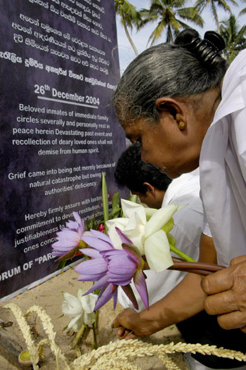 A woman places flowers at a memorial for victims of the Indian Ocean tsunami in Peraliya, Hikkaduwa, December 26, 2006. Church and temple bells will toll across Sri Lanka on Tuesday for the victims of the 2004 tsunami but commemoration ceremonies in rebel-held areas, which were the worst hit, will be deliberately low-key.