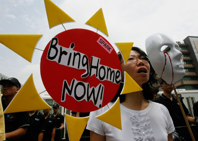 A protester holding a mask and a sun-shaped banner shouts slogans during an anti-war and anti-U.S. rally, demanding for a negotiation between the U.S. government and the Taliban for the safe return of South Korean hostages in Afghanistan, in front of the U.S. embassy in Seoul August 1, 2007.