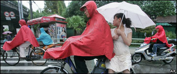 A couple ride a moped in the rain