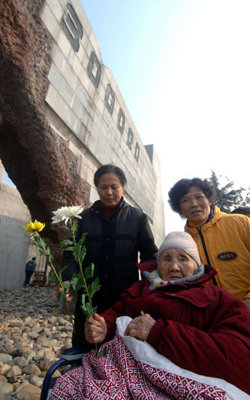 Wu Xiulan (Front), a 93-year-old survivor of the Nanjing massacre, presents a flower to the victims of the Nanjing massacre during a peace rally to mark the 69th anniversary of the Nanjing massacre committed by Japanese invading troops, in Nanjing, capital of east China's Jiangsu Province, Dec. 13, 2006.