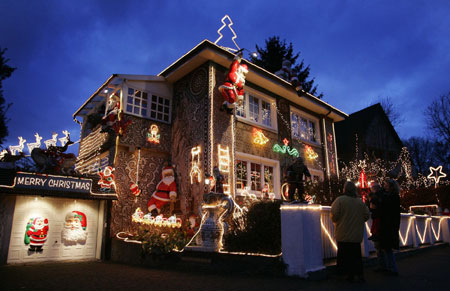 People look at a house decorated with Christmas lights in the northern German town of Hamburg December 18, 2006.