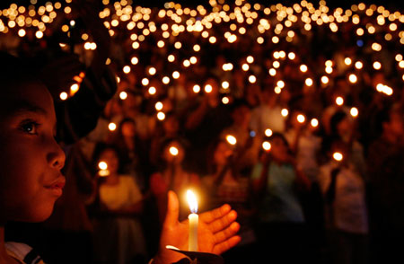An Indonesian Christian holds a candle during Christmas mass at a stadium in Jakarta December 24, 2006. Jakarta is deploying about 18,000 police and 2,000 soldiers across the capital and its outskirts ahead of Christmas, a senior official said. 