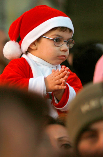 An Israeli Arab boy wears a Santa Claus hat during a procession in celebration of Christmas, in the northern town of Nazareth December 24, 2006.