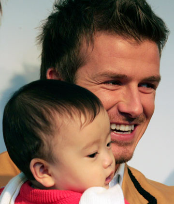 England's soccer player David Beckham holds a baby in his arms at a promotional event in Tokyo December 29, 2006.