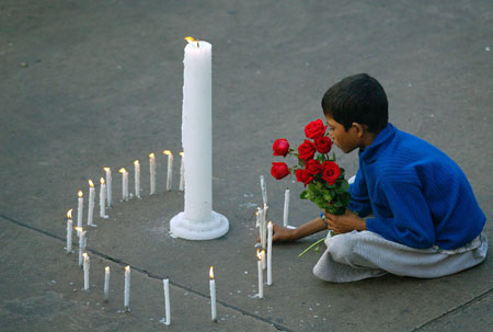 A girl with roses light candles in memory of executed former Iraqi President Saddam Hussein, near the American Center in the eastern Indian city of Kolkata December 30, 2006.