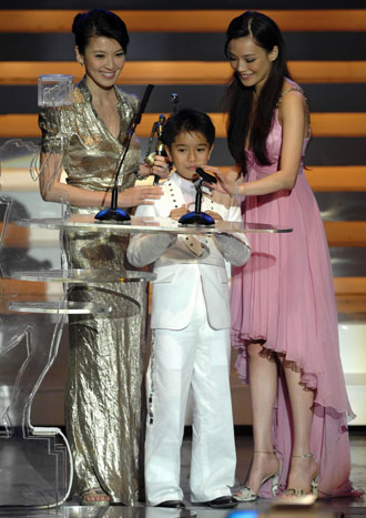 Actress Kelly Lin (L) and Shu Qi (R) present the trophy to Malaysia-born actor Gouw Ian Iskandar as he won the Best Supporting Actor Award for the movie 