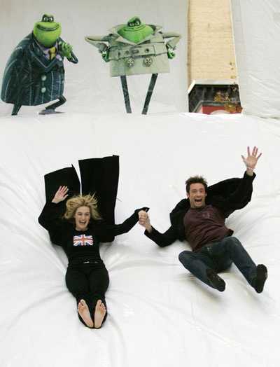 Actors Hugh Jackman (R) and Kate Winslet slide down a large inflatable toilet slide for the premiere of the animated feature 