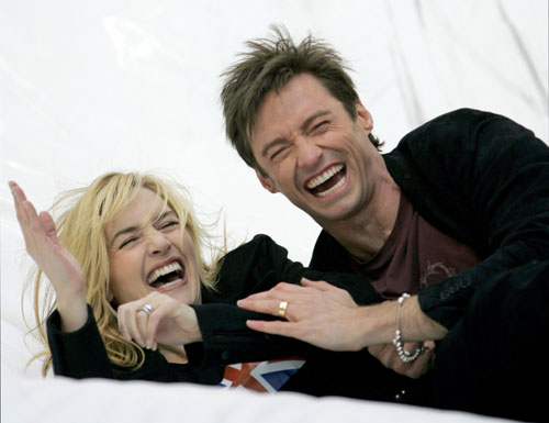 Actors Hugh Jackman and Kate Winslet laugh after sliding down a large inflatable toilet slide for the premiere of the animated feature 