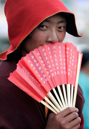 A Tibetan monk holding a red fan stands on a street in Yushu, west China's Qinghai province, July 26, 2007.