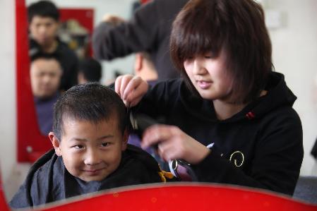 A child gets a haircut at a barbershop in Hefei
